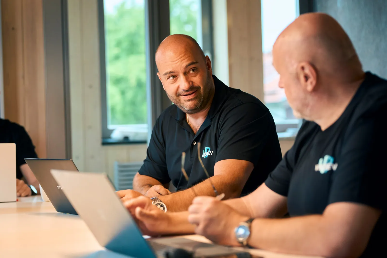 Zwei Kollegen tauschen sich am Laptop über ein Projekt aus